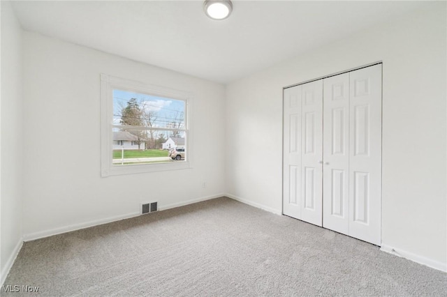 unfurnished bedroom with baseboards, visible vents, carpet, and a closet