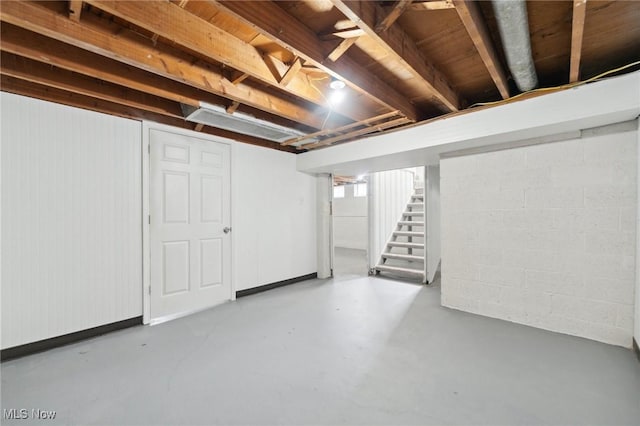 below grade area featuring concrete block wall and stairs