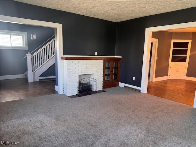 204 N Spring St, Loudonville, OH 44842 - unfurnished living room featuring carpet floors, baseboards, stairway, a fireplace, and a textured ceiling