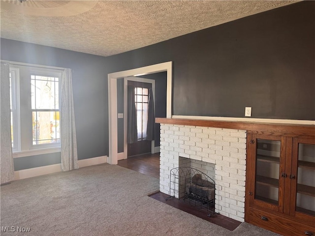 204 N Spring St, Loudonville, OH 44842 - unfurnished living room featuring dark colored carpet, a textured ceiling, a fireplace, and baseboards