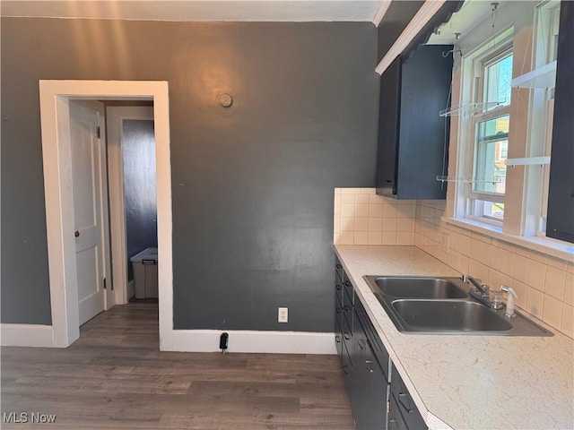 204 N Spring St, Loudonville, OH 44842 - kitchen featuring a sink, backsplash, baseboards, dark wood finished floors, and light countertops