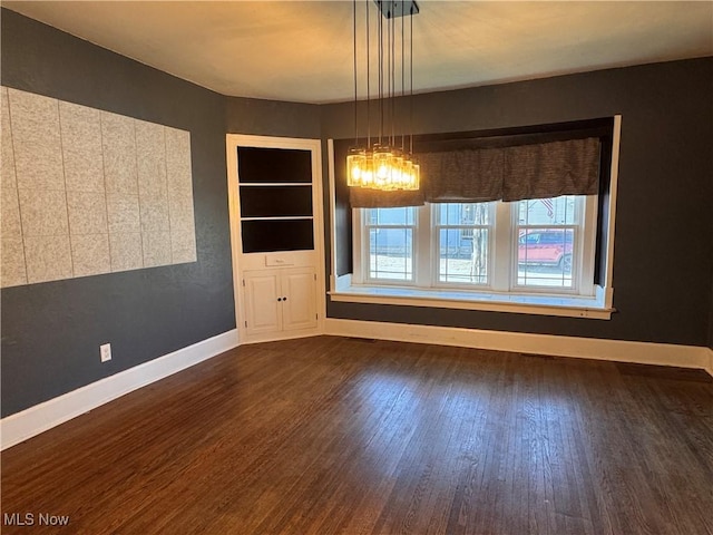 204 N Spring St, Loudonville, OH 44842 - unfurnished dining area featuring dark wood-type flooring, baseboards, and a chandelier