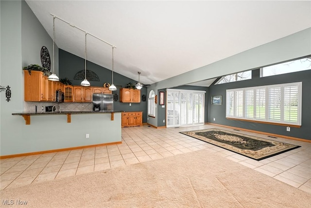 kitchen featuring a breakfast bar, appliances with stainless steel finishes, high vaulted ceiling, and light tile patterned floors