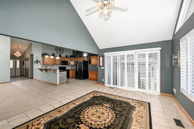 living room with high vaulted ceiling, ceiling fan with notable chandelier, light tile patterned floors, baseboards, and visible vents