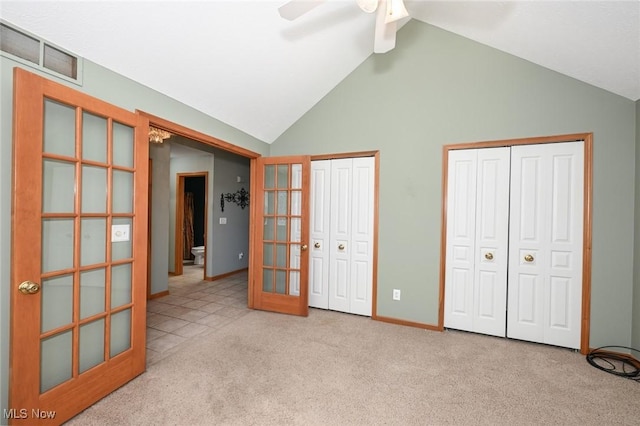 unfurnished bedroom featuring high vaulted ceiling, multiple closets, ceiling fan, baseboards, and carpet flooring