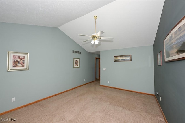 empty room with vaulted ceiling, a ceiling fan, light carpet, baseboards, and visible vents
