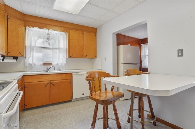 kitchen featuring plenty of natural light, a kitchen breakfast bar, white appliances, and a sink