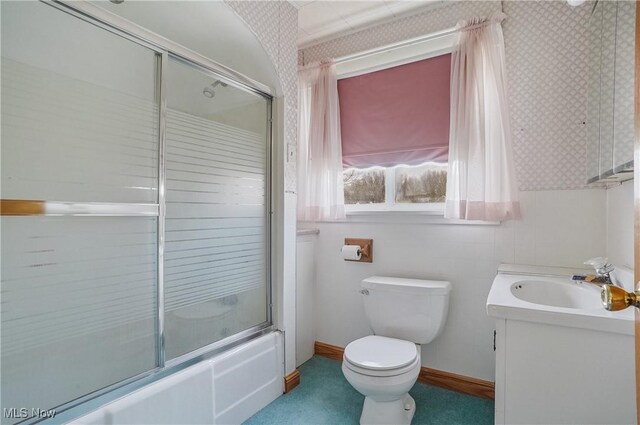 bathroom with wallpapered walls, toilet, vanity, and enclosed tub / shower combo
