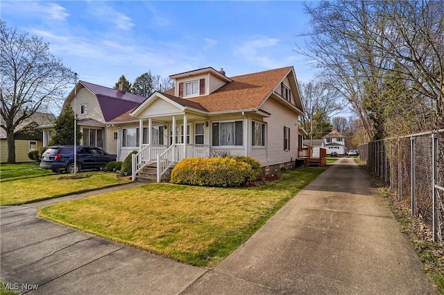bungalow featuring fence, a front lawn, driveway, and covered porch