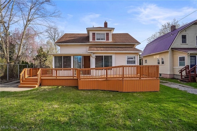 back of house featuring a wooden deck, a lawn, a chimney, and a sunroom