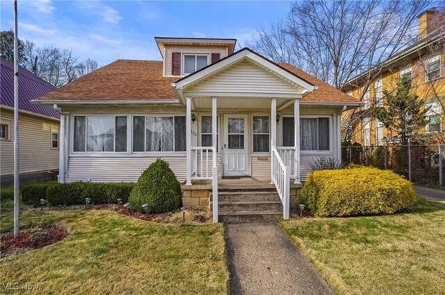 bungalow-style house featuring fence, a front lawn, and roof with shingles