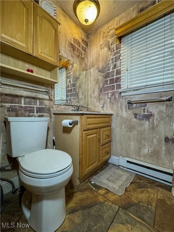 half bathroom featuring a baseboard heating unit, a textured ceiling, a sink, toilet, and stone finish floor