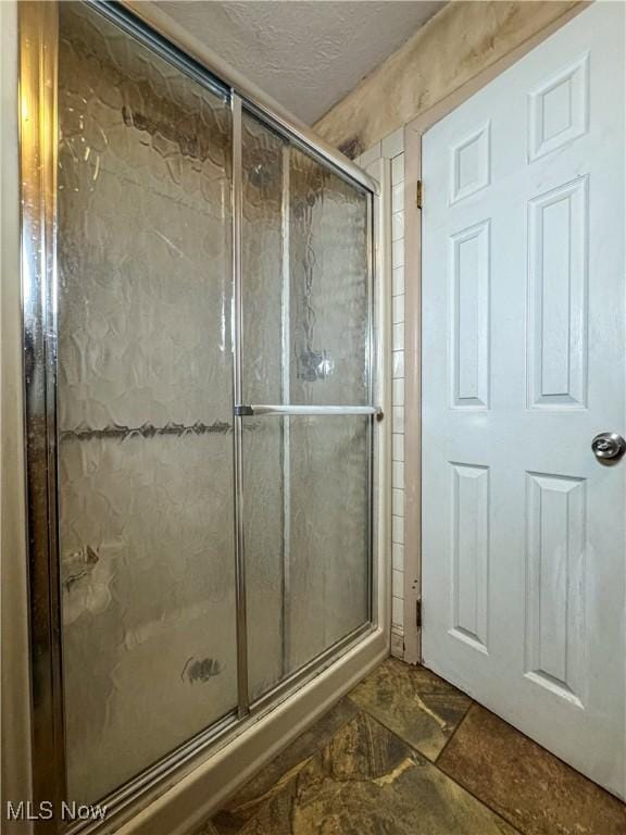 full bathroom with a textured ceiling and a shower stall