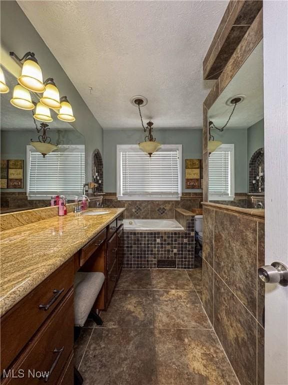 bathroom featuring a garden tub, toilet, vanity, and a textured ceiling