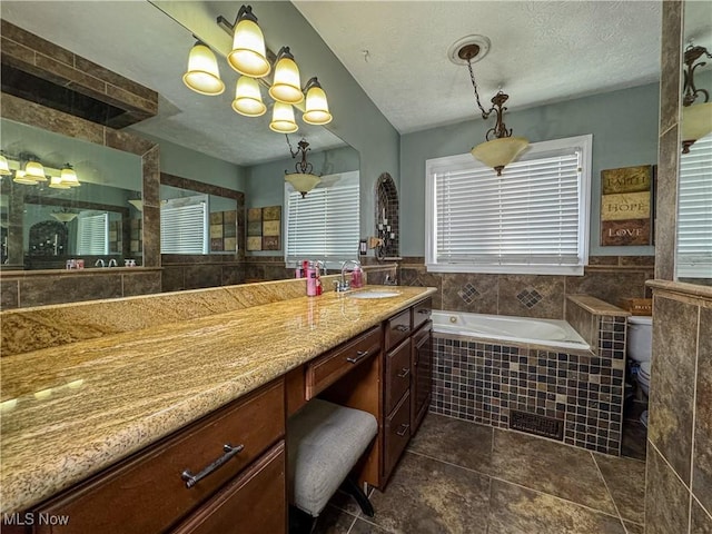 full bathroom with a bath, a textured ceiling, vanity, and a notable chandelier