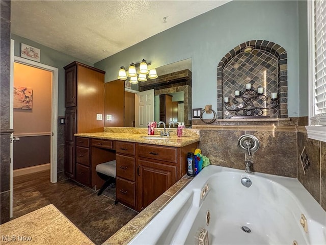 full bathroom with vanity, a textured ceiling, and a jetted tub