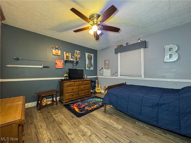bedroom with wood finished floors, a textured ceiling, baseboards, and ceiling fan