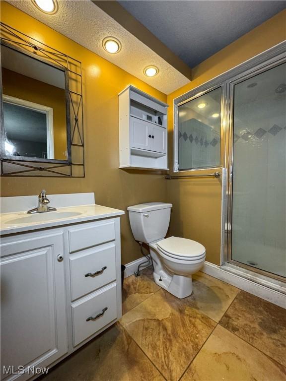 full bathroom with baseboards, a shower stall, toilet, and vanity