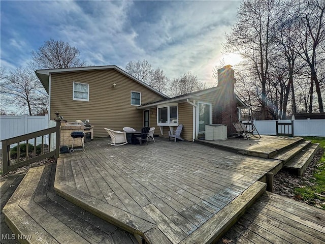back of house with outdoor dining area, a chimney, fence, and a deck