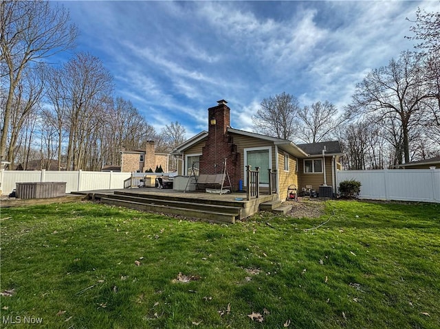 back of house featuring a wooden deck, a yard, a chimney, and fence