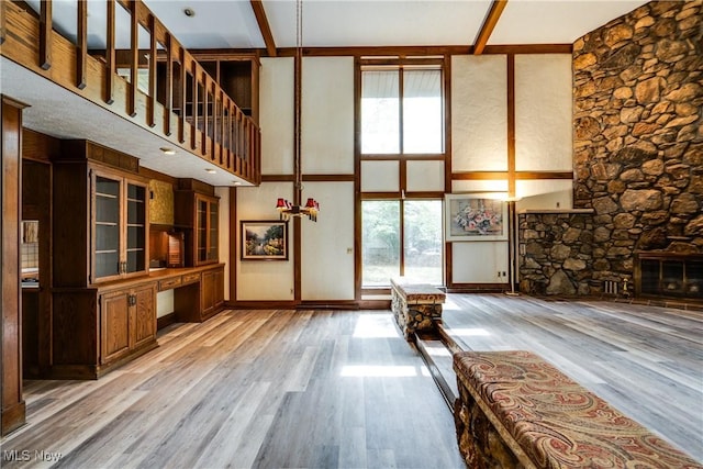 1809 Heritage Cir, Dover, OH 44622 - unfurnished living room featuring built in study area, light wood-type flooring, a towering ceiling, a fireplace, and baseboards