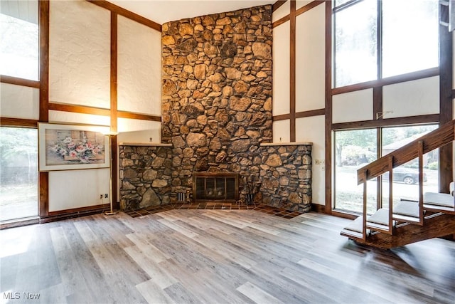 1809 Heritage Cir, Dover, OH 44622 - unfurnished living room with stairway, wood finished floors, a stone fireplace, baseboards, and high vaulted ceiling