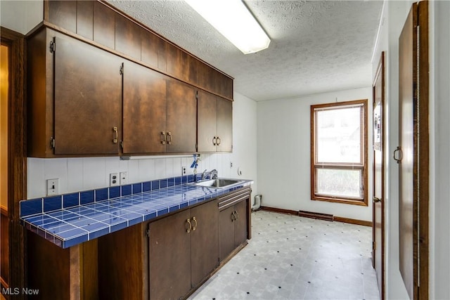 1809 Heritage Cir, Dover, OH 44622 - kitchen featuring a sink, a textured ceiling, tile countertops, light floors, and baseboards