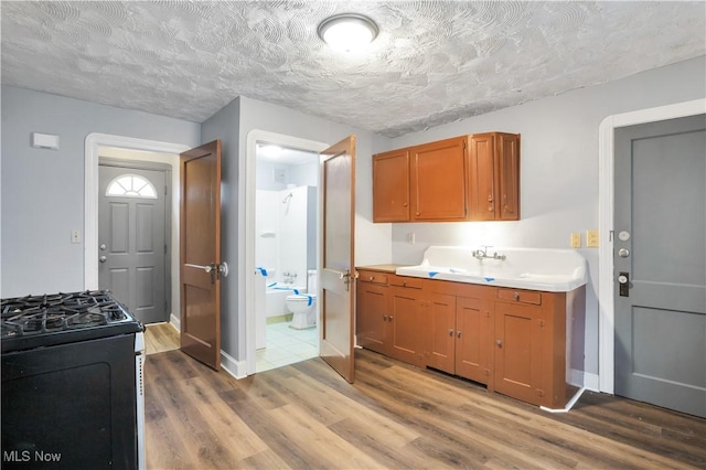 3533 Carlyle Ave, Cleveland, OH 44109 - kitchen featuring range with gas stovetop, wood finished floors, a sink, brown cabinets, and light countertops