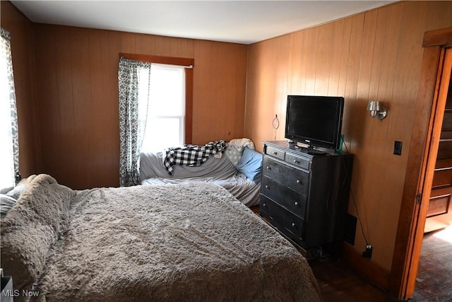 bedroom with wooden walls and dark wood finished floors