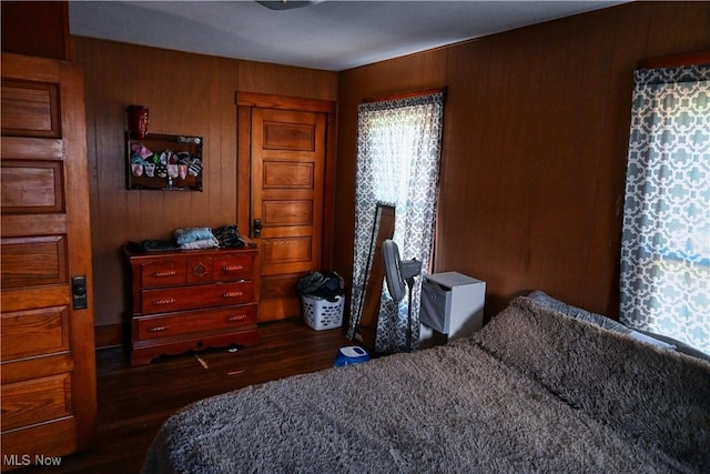bedroom featuring wood finished floors and wooden walls