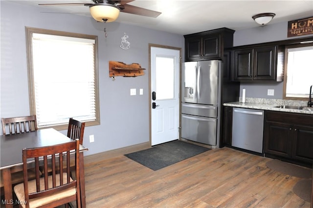 kitchen featuring a ceiling fan, a sink, light wood-type flooring, baseboards, and appliances with stainless steel finishes