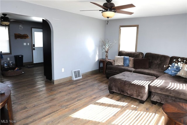 living area with ceiling fan, arched walkways, wood finished floors, and visible vents