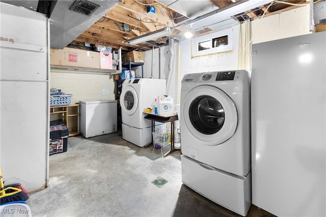 laundry room with concrete block wall, visible vents, independent washer and dryer, and laundry area