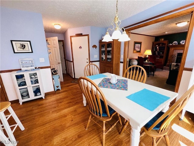 dining room with wood finished floors, a textured ceiling, and a notable chandelier