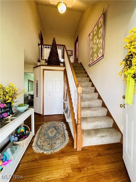 entryway featuring wood finished floors, high vaulted ceiling, and stairway