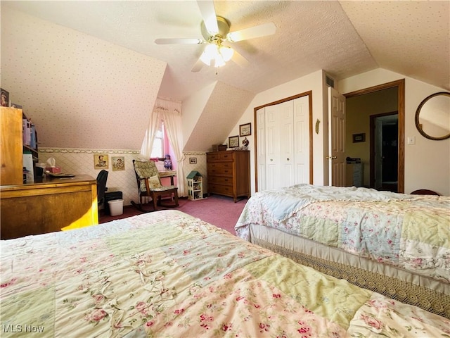 bedroom featuring carpet flooring, vaulted ceiling, wallpapered walls, a closet, and ceiling fan