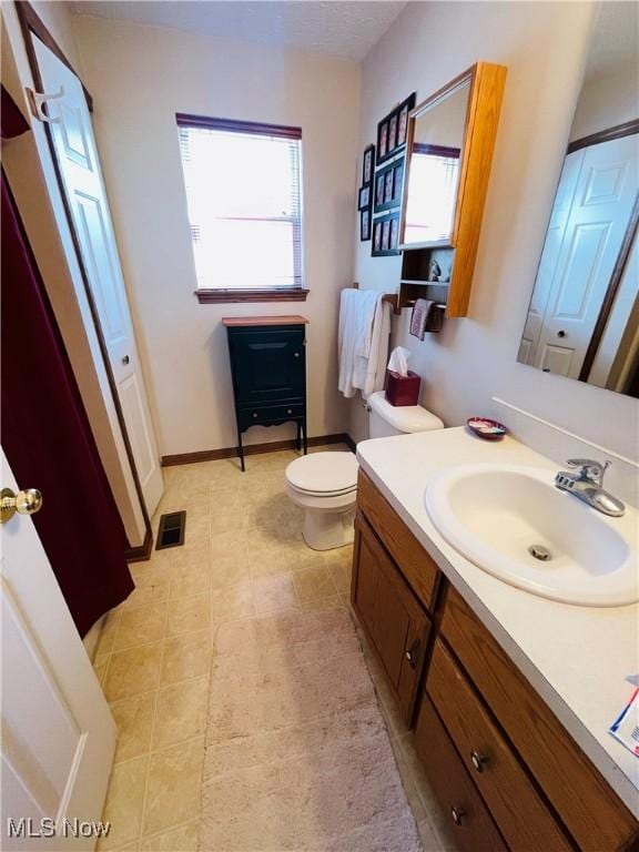 bathroom featuring tile patterned floors, toilet, baseboards, visible vents, and vanity