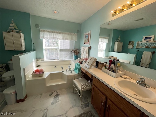 full bath with marble finish floor, a garden tub, toilet, vanity, and a textured ceiling