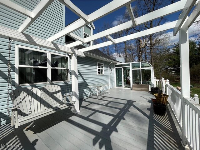 deck with a pergola and a sunroom