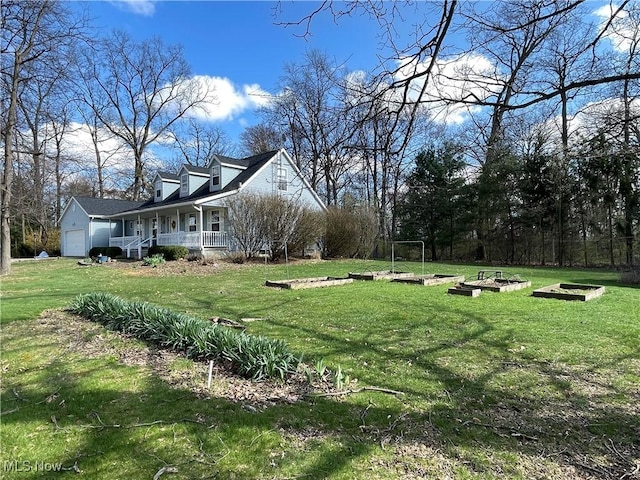 view of yard with an attached garage, a garden, and a porch