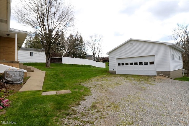 view of yard featuring fence, an outbuilding, and a detached garage