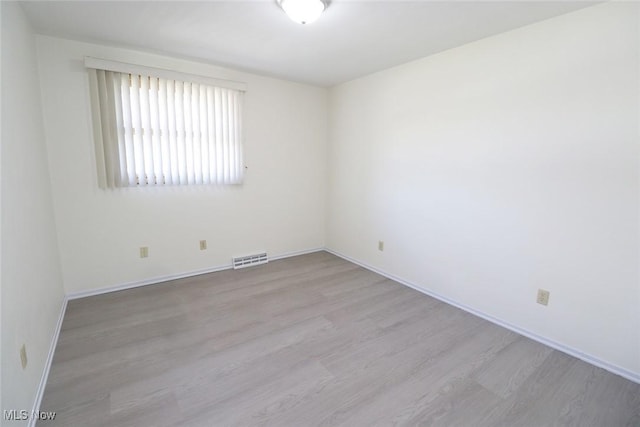 empty room with visible vents, baseboards, and wood finished floors