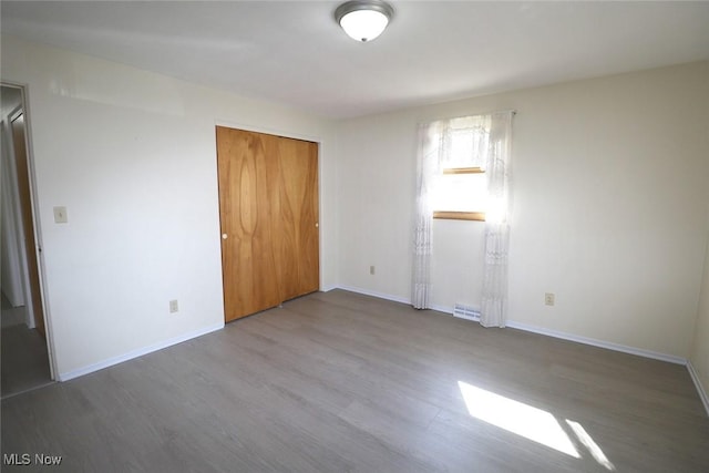 unfurnished bedroom with wood finished floors, a closet, and baseboards