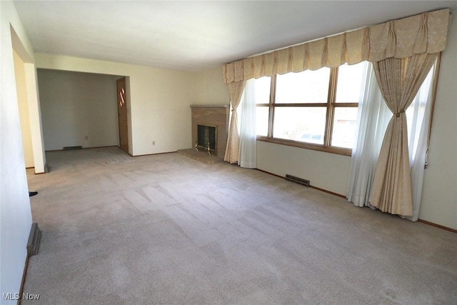 unfurnished living room featuring baseboards, a brick fireplace, visible vents, and carpet