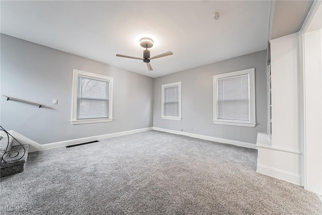 carpeted empty room with ceiling fan, baseboards, and visible vents