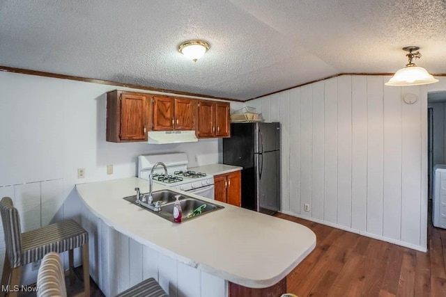 kitchen featuring under cabinet range hood, light countertops, freestanding refrigerator, a textured ceiling, and white gas range oven