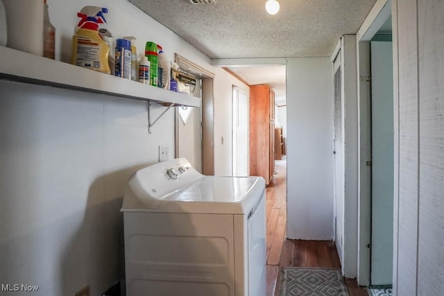 laundry area featuring laundry area, a textured ceiling, hardwood / wood-style flooring, and washer / clothes dryer