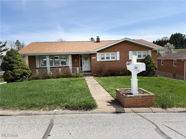 view of front of home featuring roof with shingles, a porch, a front yard, and a chimney