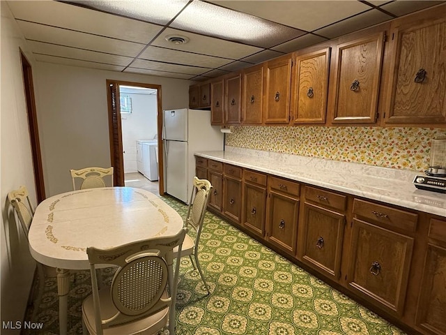 kitchen with tasteful backsplash, a drop ceiling, visible vents, freestanding refrigerator, and light countertops