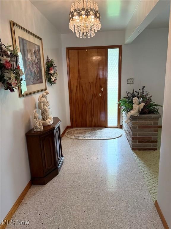 foyer entrance with baseboards and a notable chandelier